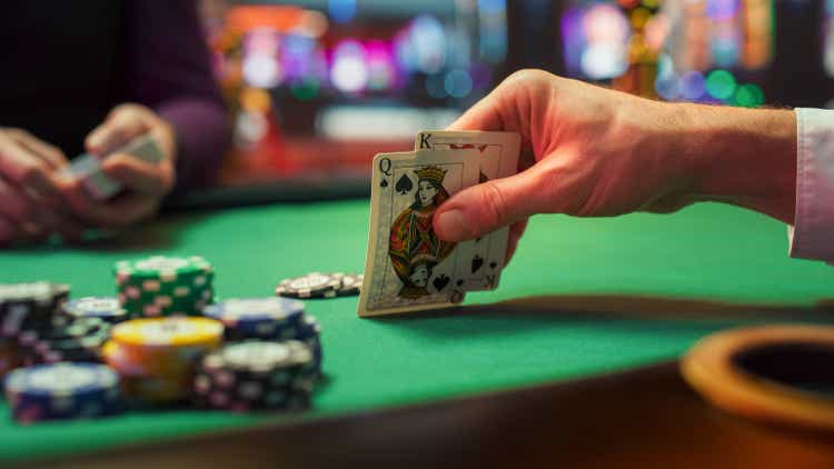 Close Up Shot On Hand Of Anonymous Poker Player Checking Playing Cards He Was Dealt. Professional High Stakes Gambler Making A Bet, Thinking Of Strategy, Counting Chips In Competitive Tournament.