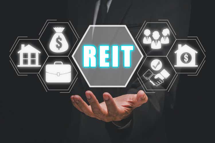 REIT, Real Estate Investment Trust concept, Businessman hand holding Real Estate Investment Trust icon on virtual screen.