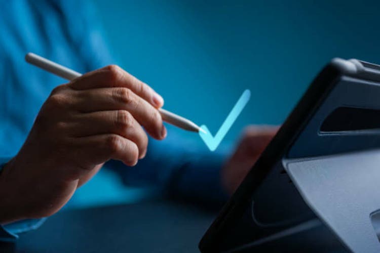Man using tablet with a pen ticks correct mark, top service quality assurance, guarantees, standards, ISO certification, and standardization concept. Satisfaction experience of products and services.