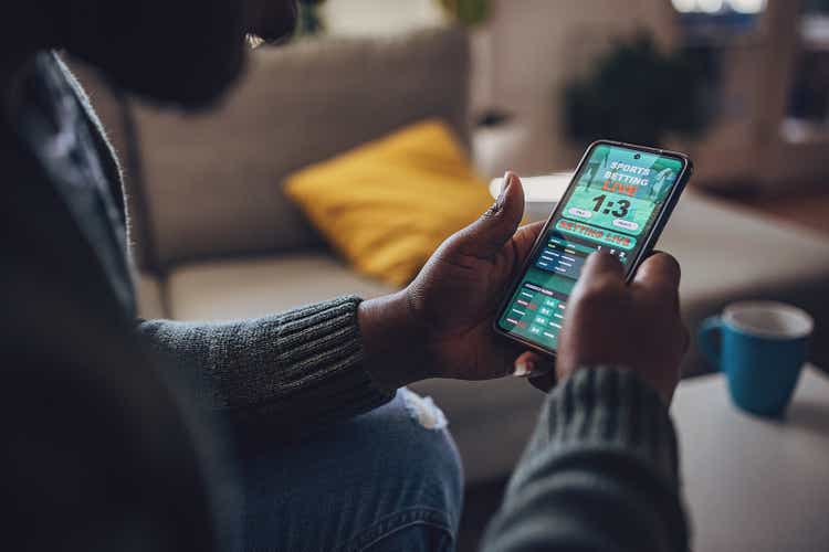 Man Engrossed in Live Sports Betting on Smartphone