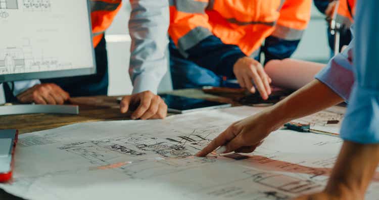 Closeup of team of industrial engineers meeting analyze machinery blueprints consult project on table in manufacturing factory. Working in manufacturing plant or production plant.