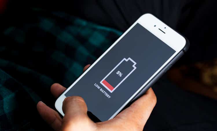 Zelluläre Probleme und Energiekonzepte. Nahaufnahme einer männlichen Hand, die ein Smartphone mit einem Zeichen für einen niedrigen Batteriestand auf dem Bildschirm hält.