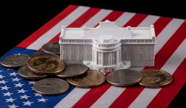 The symbolic residence of the US President, the White House, against the backdrop of the American flag and coins