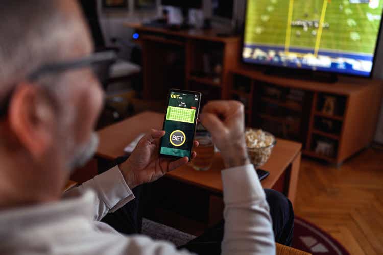 Mature men using smart phone for sports betting.