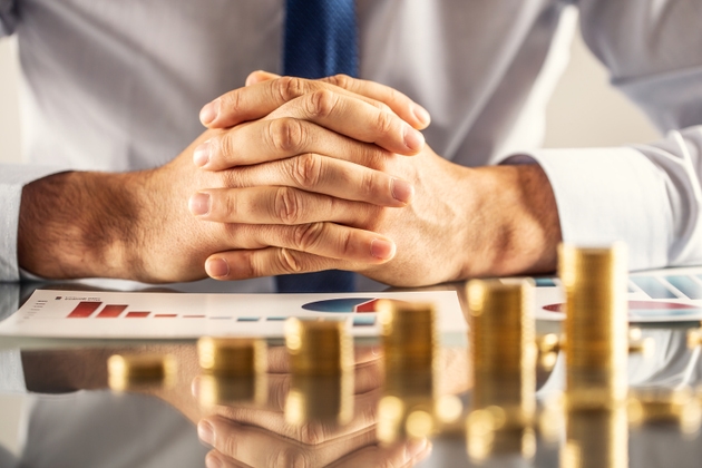 A symbol of profit and saving money. Businesman"s hands and growing graph from gold coins.