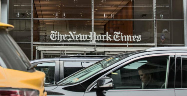 Cars and taxi cabs drive in front of The New York Times newspaper company sign above the entrance to their corporate headquarters in Times Square, Manhattan, NYC.
