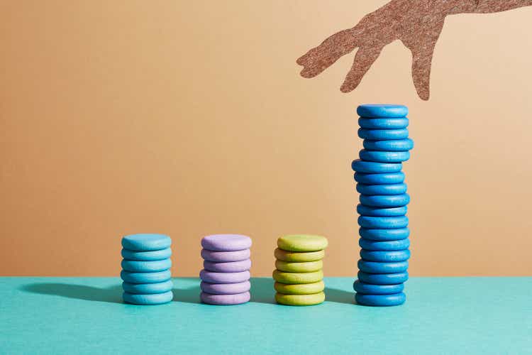 A hand reaching for a coin on top of a large stack of coins