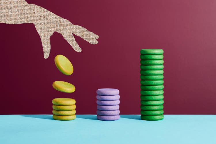 A hand dropping coins onto a stack