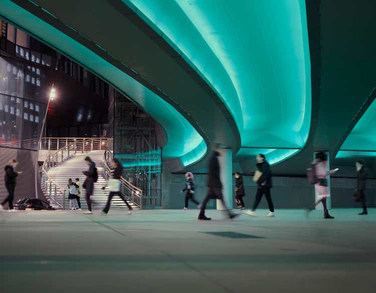 Evening commute with people passing a LED illuminated viaduct at a modern business district