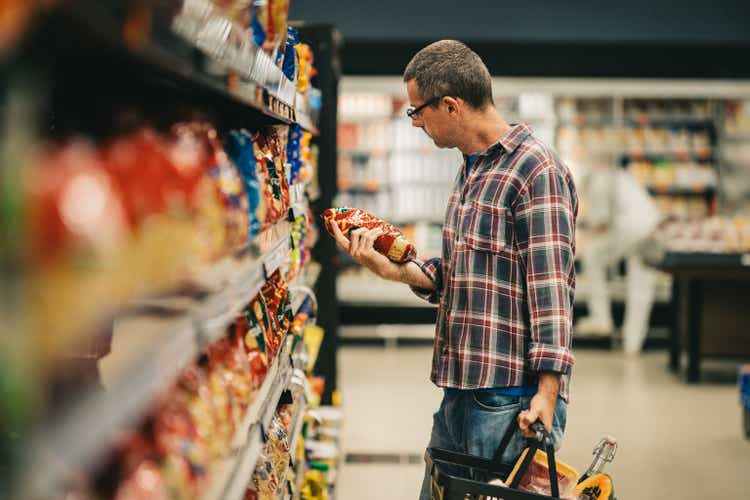 Man reading a label while grocery shopping in a supermarket aisle