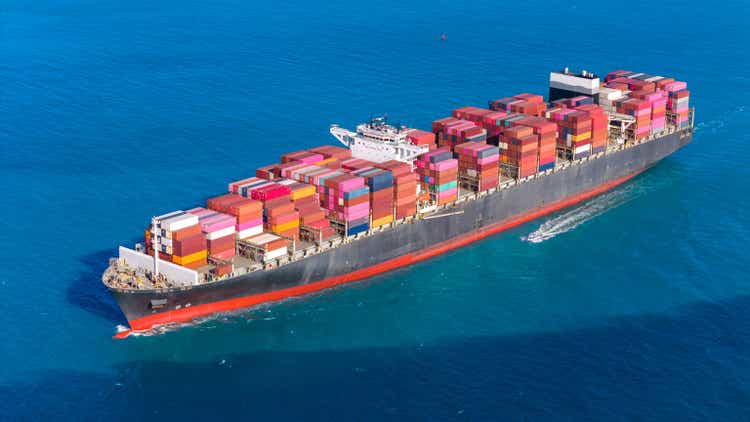 Top view Container ship full capacity approaching the port by a tugboat occupying the port International Container ship loading, unloading at sea port, Freight Transportation, Shipping, Vessel. Logistics, import export, Transportation. Global transport b