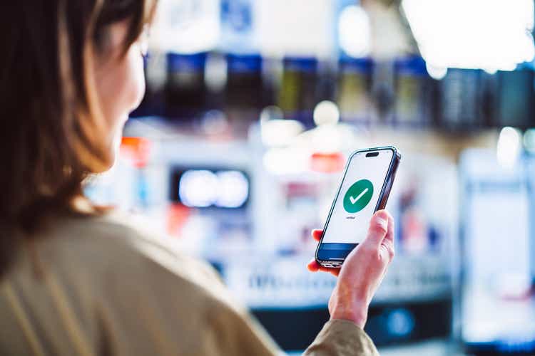 Cheerful Asian businesswoman confirming travel schedule using smartphone app at airport