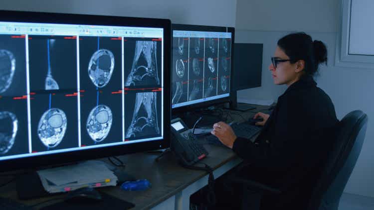 Radiologist analyzing MRI scans on multiple computer monitors