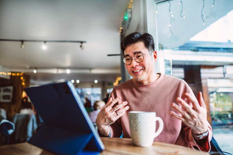 Confident businessman having a video conference call on digital tablet while having coffee break in cafe. The concept of remotely working.