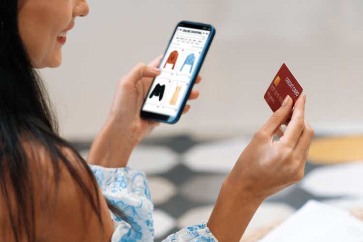 Young woman using smartphone with credit card for internet banking. Blithe