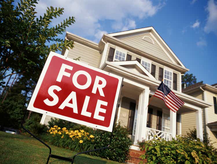 House with American flag and "for sale" sign, low angle view