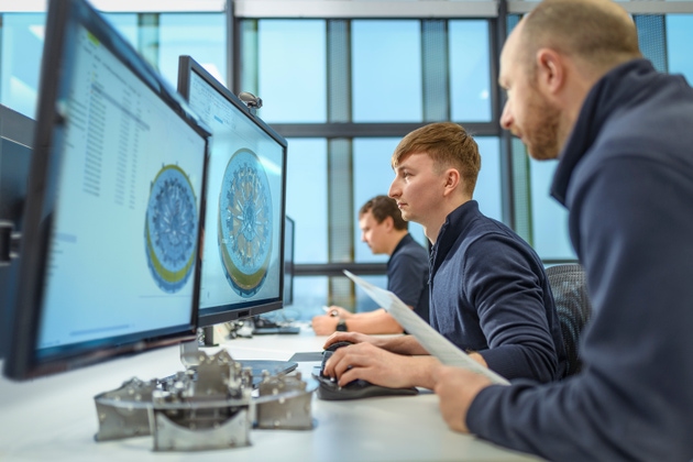Apprentice studying CAD on screen in engineering factory