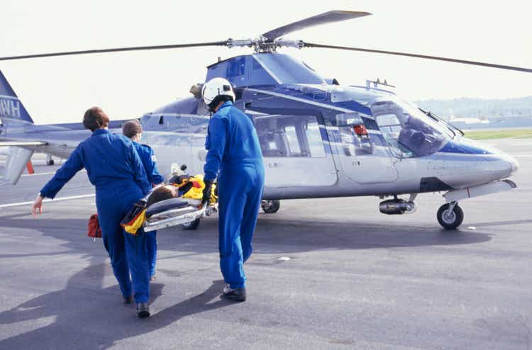 Nurses and pilot carrying patient on stretcher to helicopter