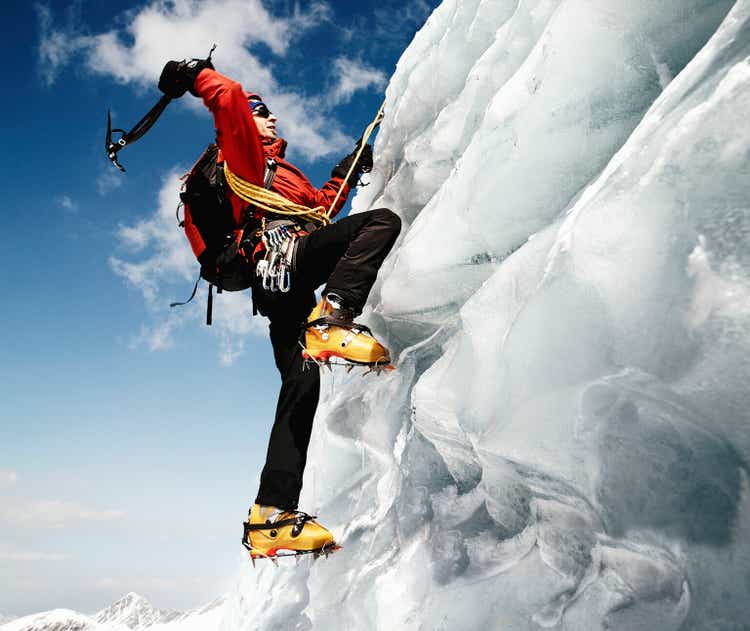 Male mountain climber on ice-covered rock face, low angle view