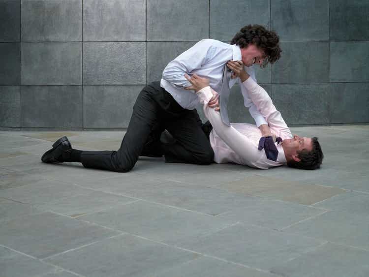 Two businessmen fighting, younger man grabbing colleague