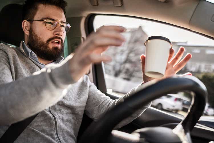 Businessman driving his car holding cup of coffee having car accident