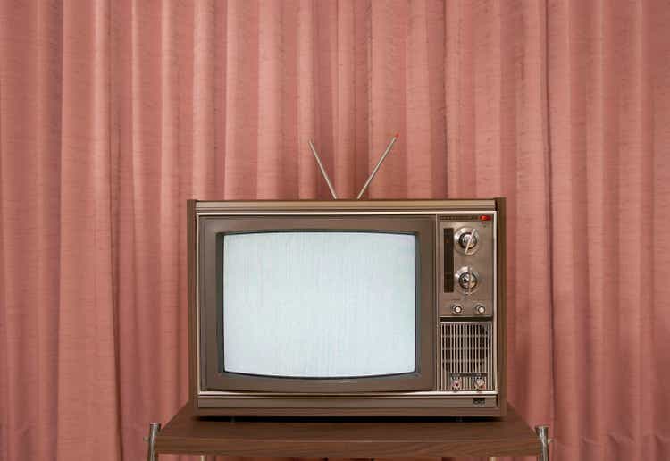 Old television on stand, in front of curtain