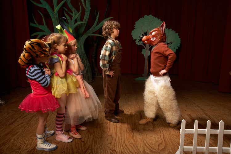 Children (5-12) acting on stage, one boy confronting bad wolf