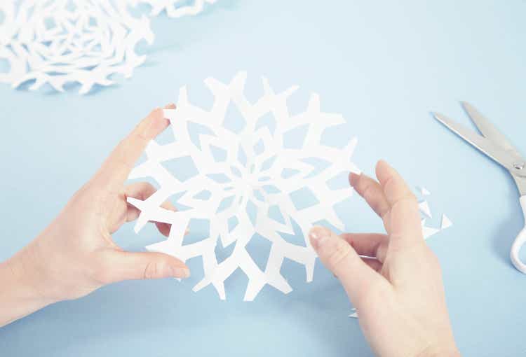 Woman making paper snowflakes, close-up of hands