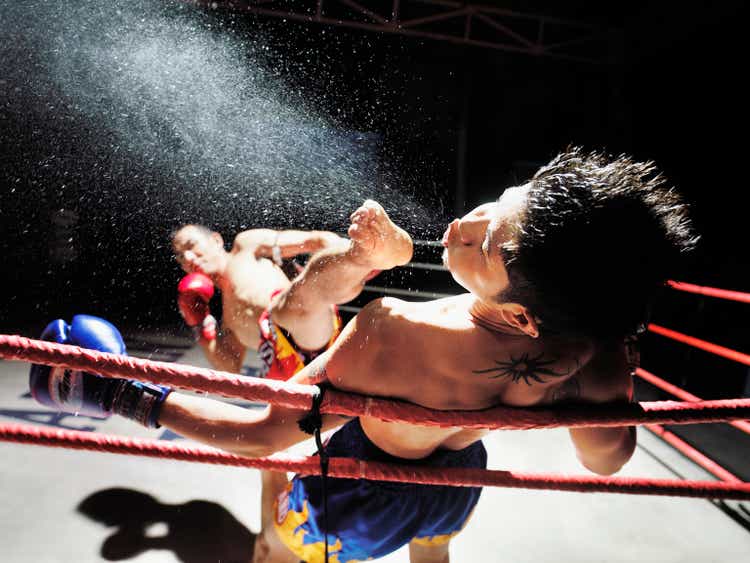 Thai boxing match, one boxer kicking another in face