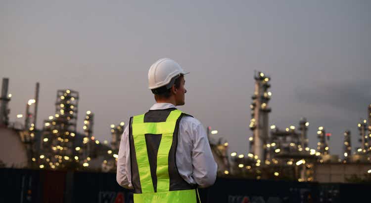 The chemical engineer working the late night shift at the petroleum oil refinery in an industrial estate. Chemical engineering, fuel and power generation, petrochemical factory industry concept