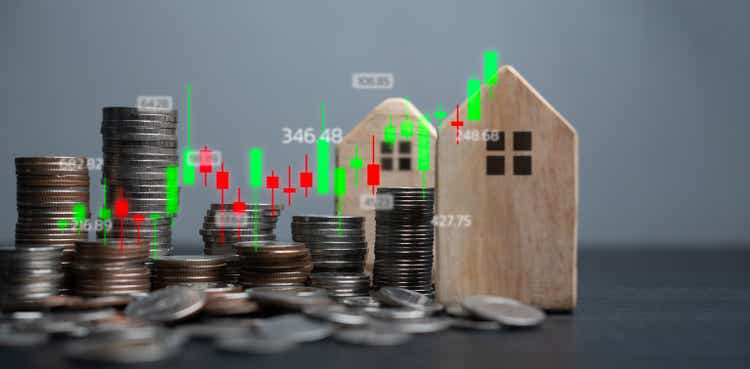 Real Estate Investment Analysis. coins and wooden houses with a stock market graph overlay representing real estate market trends and finance property.