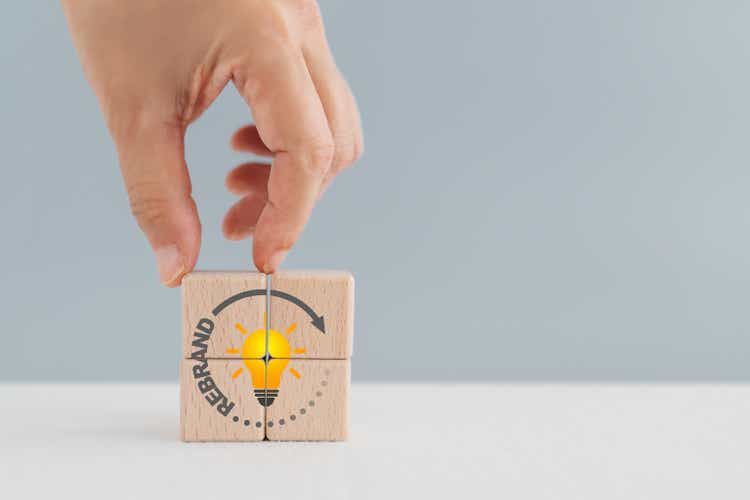 Rebrand symbol. Hand arranged wooden cube blocks with word "rebrand" on circle line and bright yellow light bulb inside. Business and rebrand concept. Copy space