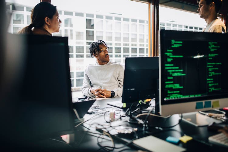 Male and female software engineers discussing during team meeting at office