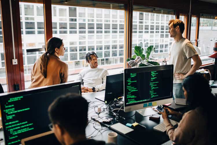 Multiracial male and female computer programmers discussing at tech-startup office