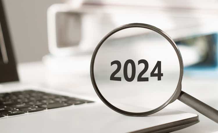 Photo of a magnifying glass with word numbers 2024 on an office desk. Focused on business concept. Search new idea