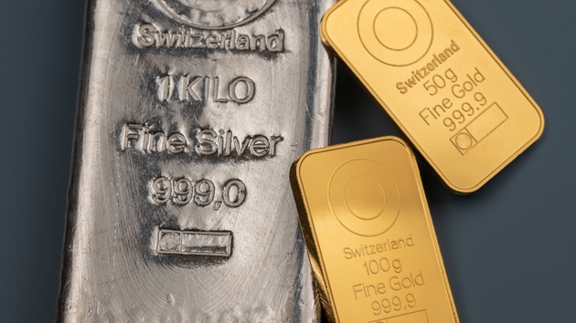 Two minted gold bars and silver cast bar on a blue