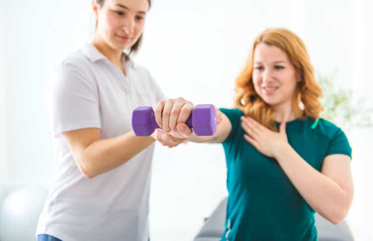 Modern rehabilitation physiotherapy working with client holding dumbbells