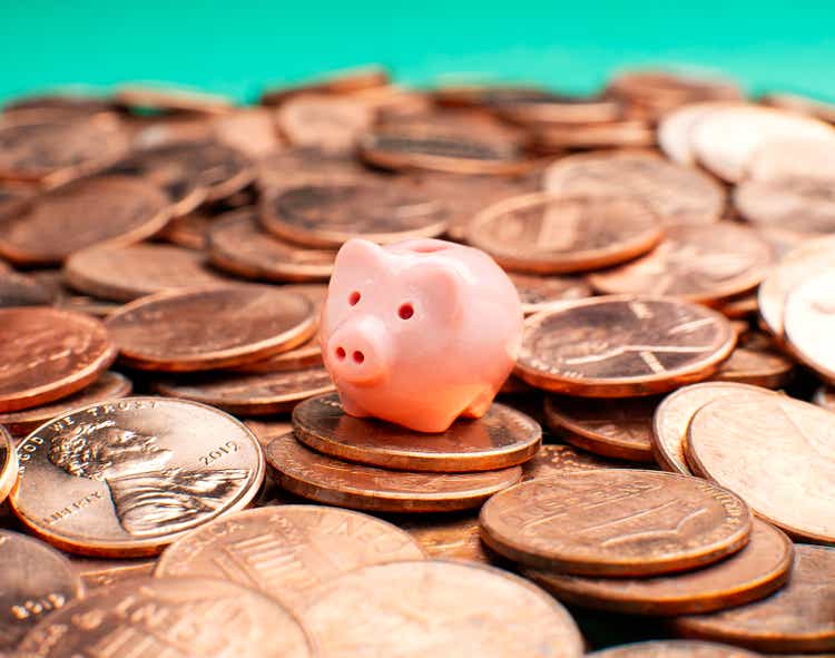 Savings concept - Tiny piggy bank on pennies