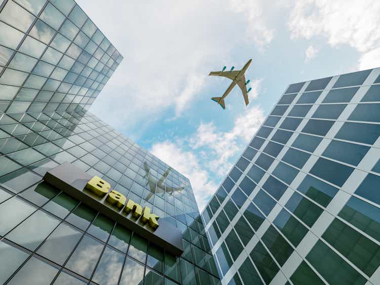 Big airplane flying over bank buildings