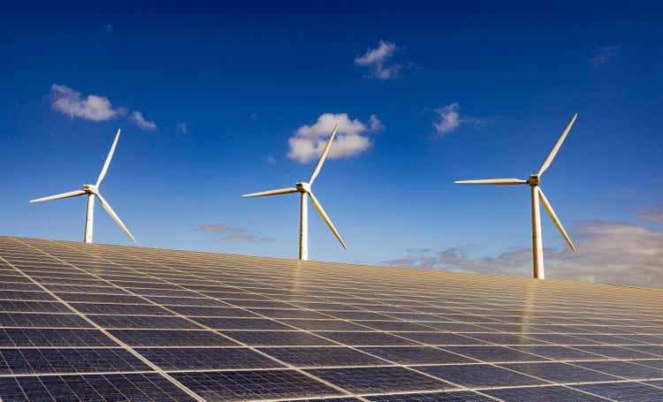 solar panel and wind turbine at low angle against blue sky