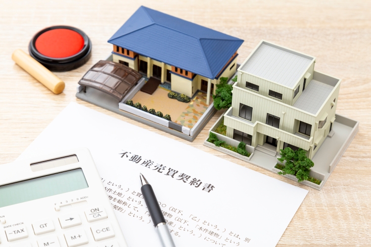 A house model and a contract are on the desk.