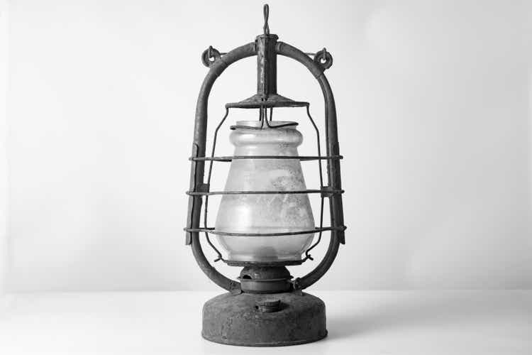 Old vintage kerosene lamp on a white wall background.