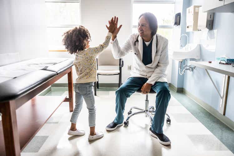 Doctor high fiving young girl in exam room