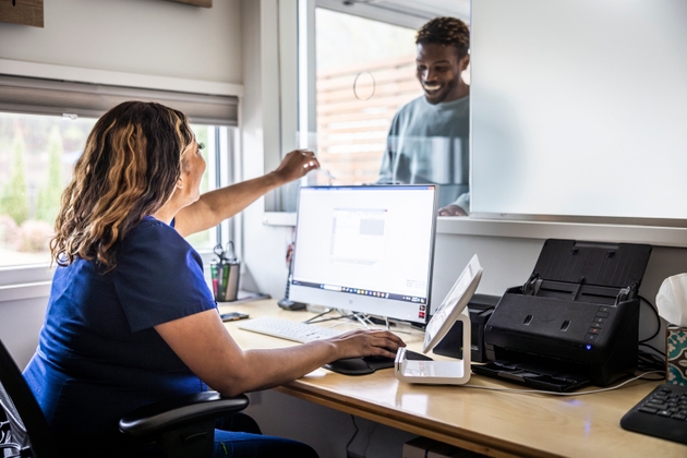 Female nurse accepting payment from patient at reception desk in doctor