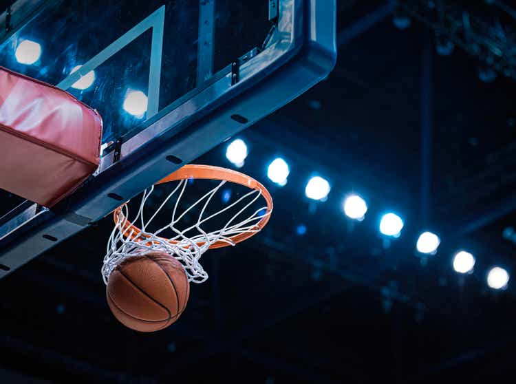 Basketball scoring a basket as it goes through the hoop