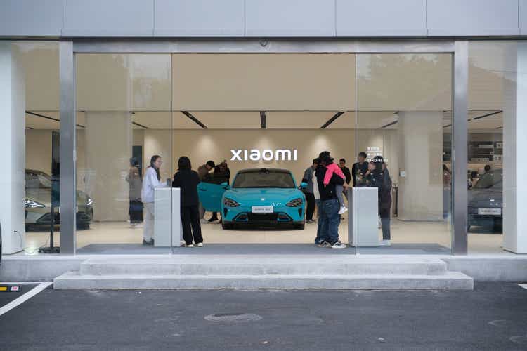 customers at Xiaomi ev store test SU7 electric car