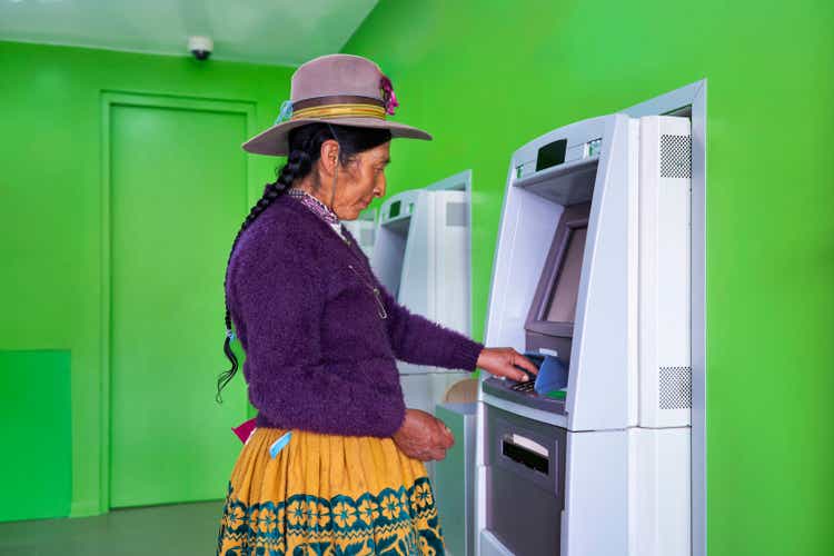 Quechua woman from the Andes taking money from an ATM. Indigenous communities already have access to electronic money