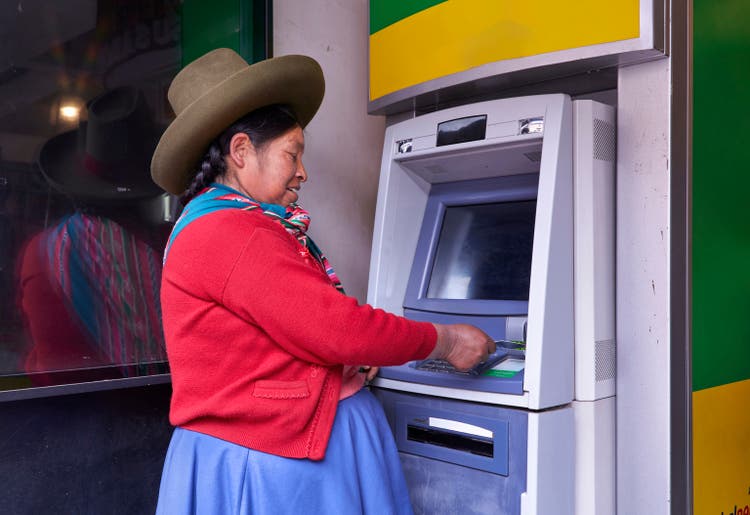 woman from an indigenous Quechua community in Peru, South America, withdrawing money from an ATM with a credit card