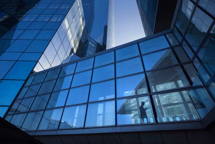 Modern office buildings with silhouette of businessman crossing elevated overpass