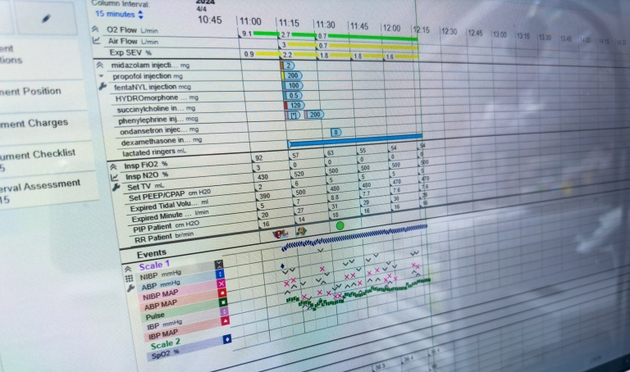 Hospital monitor displaying vital signs, with medical staff in background, conveying urgency and healthcare professionalism
